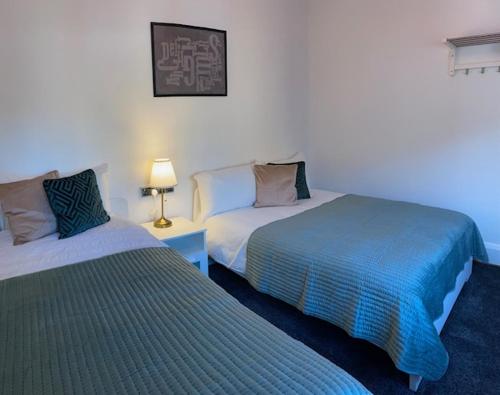 a bedroom with two beds and a lamp on a table at CAMDEN TOWN PARKWAY ROOMS in London