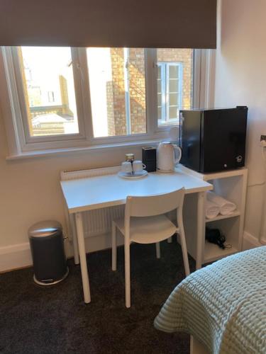 a small white table in a room with a window at CAMDEN TOWN PARKWAY ROOMS in London