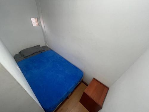 Piccola camera con letto blu e tavolo in legno. di Hostel Bogotá Niza Tu sitio a Bogotá
