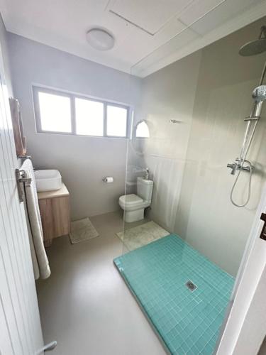 a white bathroom with a shower and a toilet at Modern Beachfront Home in Westbrook