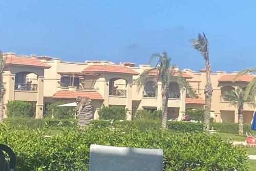 a large building with palm trees in front of it at Luxurious Villa at North Coast in El Dab‘a