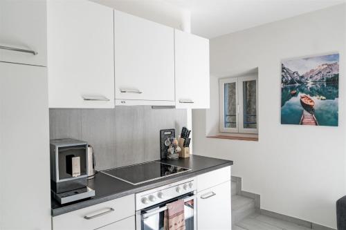 eine Küche mit weißen Schränken und einer Mikrowelle in der Unterkunft Rustico in pietra in Brissago