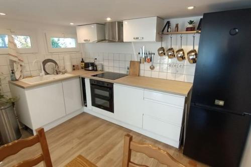 uma cozinha com armários brancos e um frigorífico preto em Maison + parking. Calme, confort em Rouen