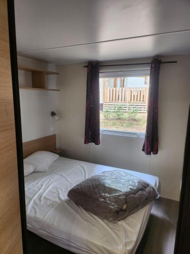 une petite chambre avec un lit et une fenêtre dans l'établissement MOBILHOME Lodge 3 chambres, 500m plage, camp 5 étoiles, à Vendres