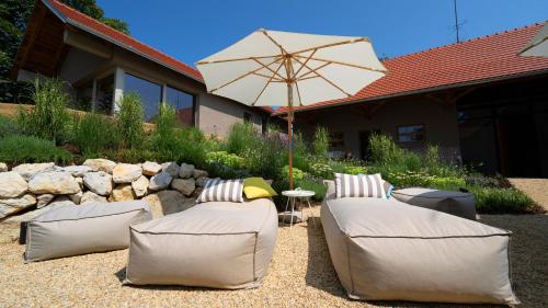 a patio with two couches and an umbrella at Premium Gardenguesthouse Mlinar with Pool & Sauna in Fokovci