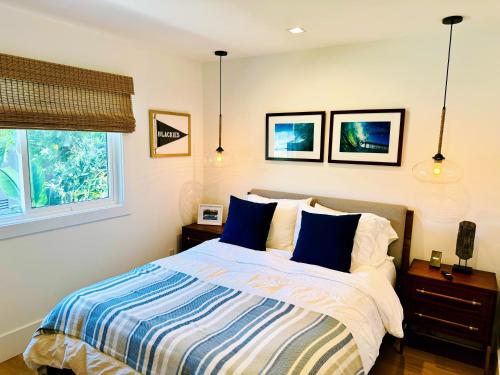 a bedroom with a bed with blue pillows and a window at Harbor Lookout - Luxury Beach Home with Coastal Views - Walk to everything! in Newport Beach