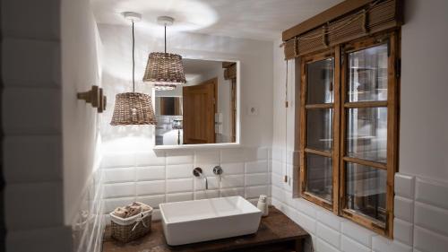 Baño blanco con lavabo y espejo en Gardenguesthouse Mlinar, en Fokovci
