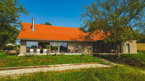 a house with an orange roof in a yard at Premium Gardenguesthouse Mlinar with Pool & Sauna in Fokovci