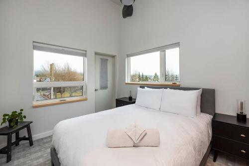 een slaapkamer met een groot wit bed en 2 ramen bij NN - The Flame - Downtown 1-bed 2-bath in Whitehorse