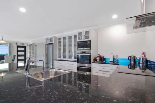 a large kitchen with white cabinets and a stainless steel sink at Pohara Beach Life in Pohara