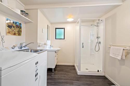 a white bathroom with a shower and a sink at Waters Edge Golden Bay in Collingwood