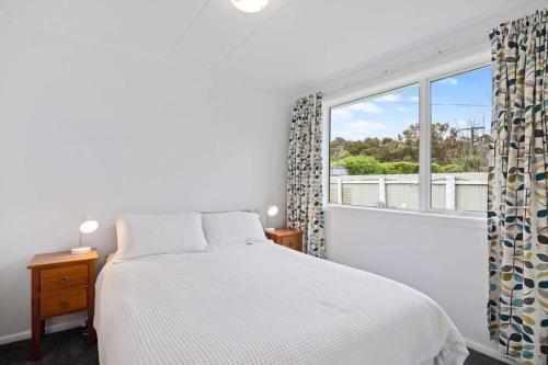 1 dormitorio con cama y ventana grande en Sunset at Parapara Beach, en Parapara 