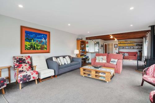 a living room with a blue couch and chairs at Parapara Beach Escape in Parapara 