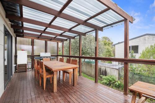 a wooden deck with a wooden table and chairs at Parapara Beach Escape in Parapara 