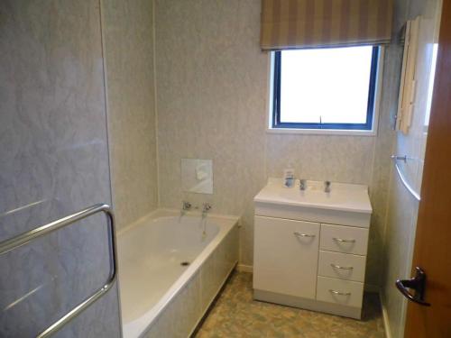 a bathroom with a tub and a sink and a bath tub at Kiwi Holidays in Cromwell in Cromwell