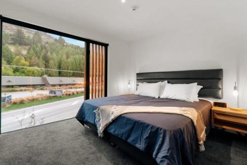 a bedroom with a large bed and a large window at The Terrace at La Residence du Parc in Queenstown