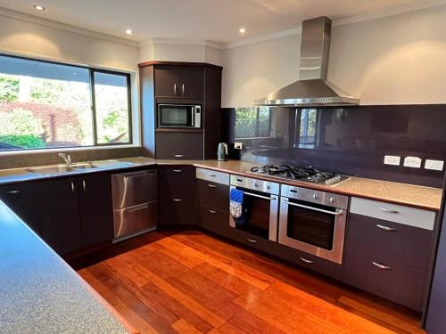 a kitchen with black cabinets and a stove top oven at Holiday on Park Avenue in Takaka