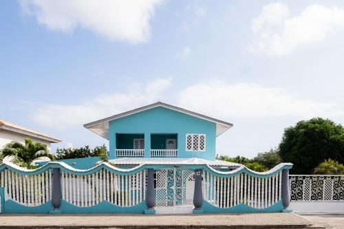 a blue house with a white fence at Villa Grandi - Cas Grandi in Willemstad