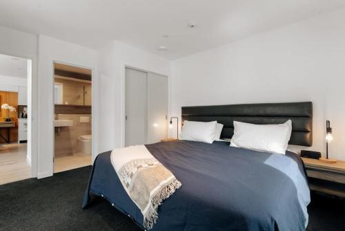 a bedroom with a large bed and a bathroom at Vue Alpine - La Residence du Parc in Queenstown