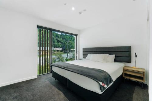 a bedroom with a large bed and a large window at Coronet Bliss - La Residence du Parc in Queenstown