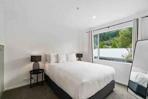 een witte slaapkamer met een bed en een groot raam bij Central Queenstown Luxury in Queenstown