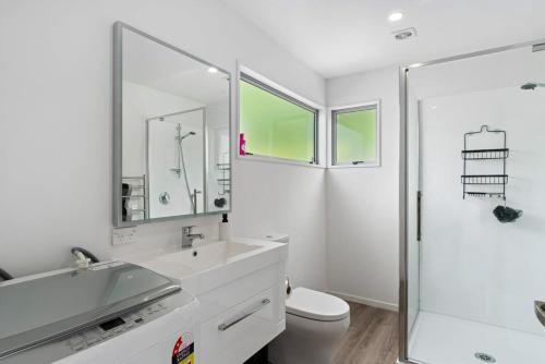 een witte badkamer met een wastafel en een douche bij Central Queenstown Luxury in Queenstown