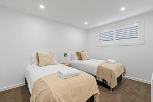 a white room with two beds and a window at Luxury Lake View Apartment in Wanaka