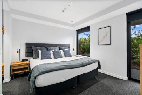 ein Schlafzimmer mit großem Bett und Fenster in der Unterkunft Cozy Coronet Peak Apartment at La Residence du Parc in Queenstown