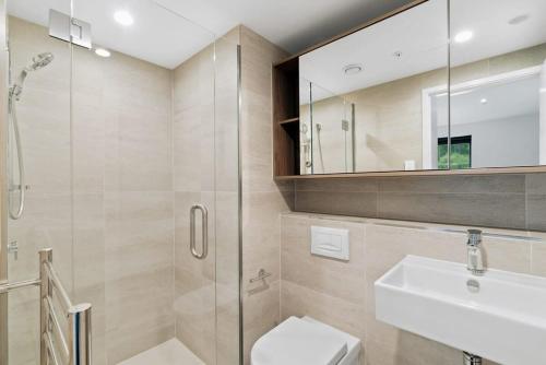 a bathroom with a shower and a toilet and a sink at Cozy Coronet Peak Apartment at La Residence du Parc in Queenstown