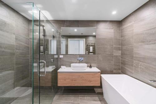 a bathroom with a tub and a sink and a shower at Lake View Studio Apartment in Wanaka