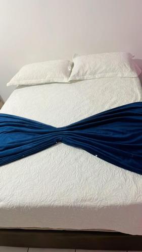 a white bed with blue sheets and pillows at Pousada Castelo in Rio Branco
