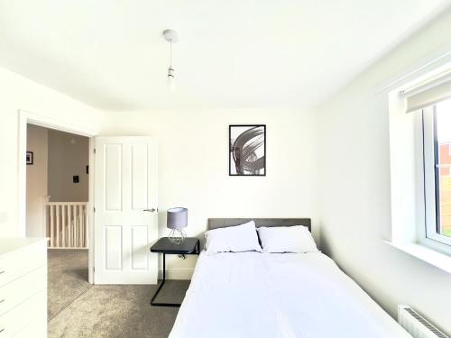 ein weißes Schlafzimmer mit einem Bett und einem Fenster in der Unterkunft BRAND NEW 3 BEDROOM HOUSE WITH GARDEN AND FREE PARKING in Wednesbury