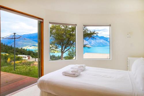 a bedroom with a white bed with large windows at Ruby's Fernhill Vista in Queenstown
