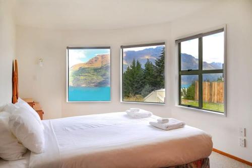 a bedroom with a bed with three windows at Ruby's Fernhill Vista in Queenstown