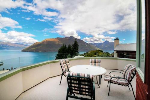 a balcony with a table and chairs and a view of the water at Ruby's Fernhill Vista in Queenstown