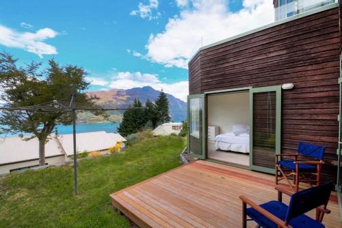 a wooden deck with a bed and chairs on a house at Ruby's Fernhill Vista in Queenstown