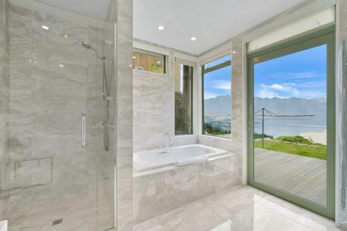 La salle de bains est pourvue d'une baignoire, d'une douche et d'une fenêtre. dans l'établissement Ruby's Fernhill Vista, à Queenstown