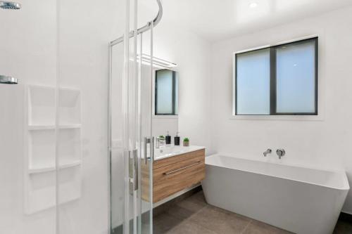a white bathroom with a tub and a sink at Vacations on Riverslea in Wanaka