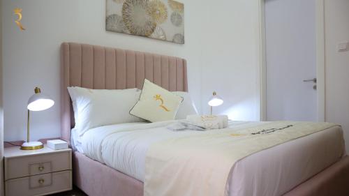 a bedroom with a bed with two lamps on it at 2BR Duplex Transit apartment Coral. in Abu Dhabi