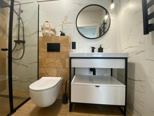 a bathroom with a sink and a toilet and a mirror at Gród Piastów - Apartamenty Ciao Bałtyk in Dąbki