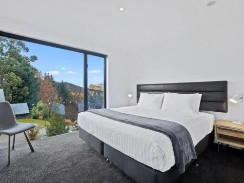 a bedroom with a large bed and a large window at Shotover Serenity in Queenstown