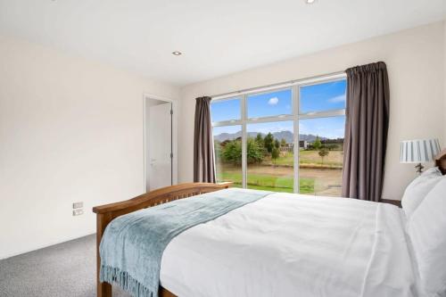 a bedroom with a bed and a large window at Sunny Dreams in Wanaka