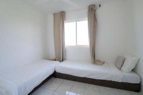 two beds in a room with a window at Villa Grandi - Cas Grandi in Willemstad