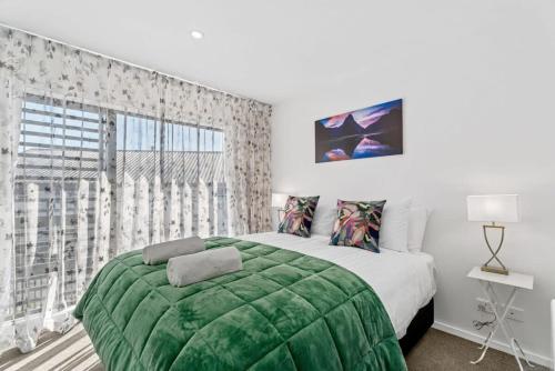 a bedroom with a green bed and a large window at Maude View in Albert Town