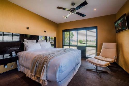 Schlafzimmer mit einem Bett, einem Stuhl und einem Deckenventilator in der Unterkunft Entertainers Dream in Christchurch