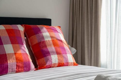 two colorful pillows sitting on a bed with a window at Albert Town Whare in Albert Town
