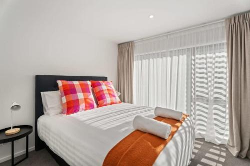 ein Schlafzimmer mit einem großen Bett mit bunten Kissen in der Unterkunft Albert Town Whare in Albert Town