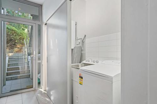 a white bathroom with a sink and a washing machine at Alpine Retreat Studio in Queenstown