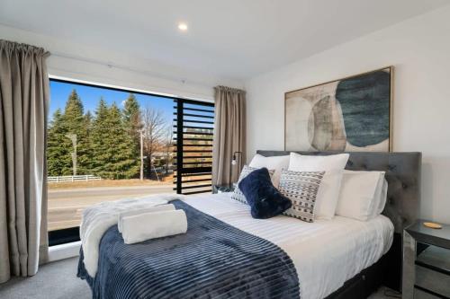 a bedroom with a large bed and a large window at Wanaka Hararei in Albert Town
