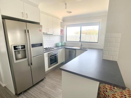a kitchen with a stainless steel refrigerator and a window at Modern Majestic - Everything you need Neat & Tidy in Orange